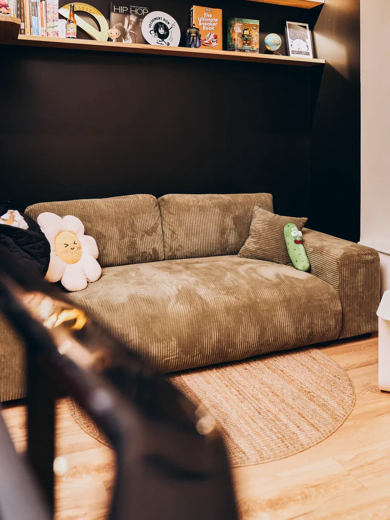 Le coin canapé du studio, sous les étagères de livres et de figurines